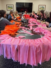 Volunteers around table applying strips of fabric to a cord