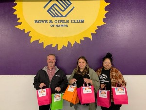 3 people in front of Boys and Girls Club sign holding care kits