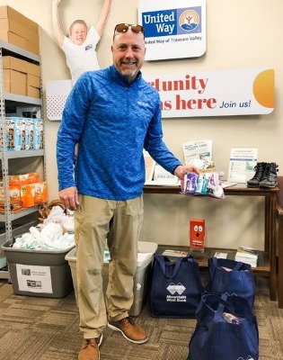 Man in front of United Way sign holding summer supply needs