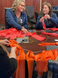 2 people talking while applying fabric to cording